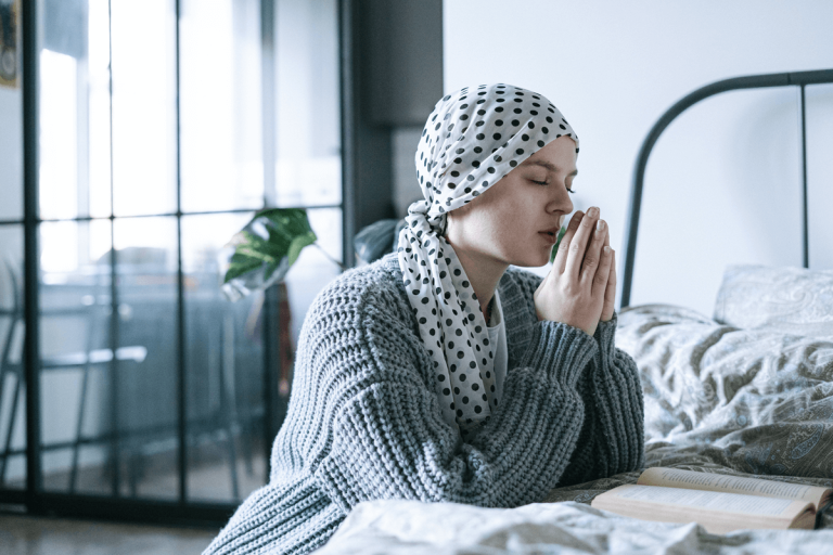 Une femme agenouillée, la tête couverte, en train de prier.